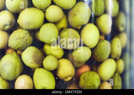 Primo piano di un grande vaso di vetro pieno di olive verdi in salamoia Foto Stock