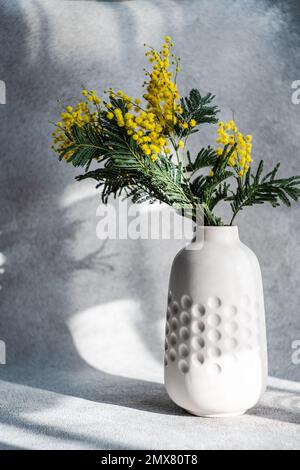 Vaso con fiori di mimosa giallo primavera in giornata di sole su tavola di pietra Foto Stock