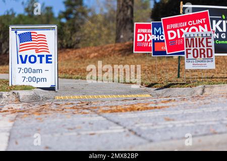 Dacula, GA / USA - 8 novembre 2022: I segni del cortile della campagna elettorale si trovano di fronte a un segno di voto in un quartiere di voto della Georgia il giorno delle elezioni. Foto Stock