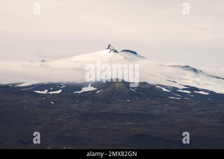 Maestoso scenario di montagna ricoperta di neve e circondata da fitte nuvole in un giorno coperto in Islanda Foto Stock