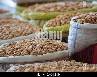 Mucchio di deliziosi pistacchi messi in sacchetti di plastica in stalla con vari tipi di noci in commercio Foto Stock