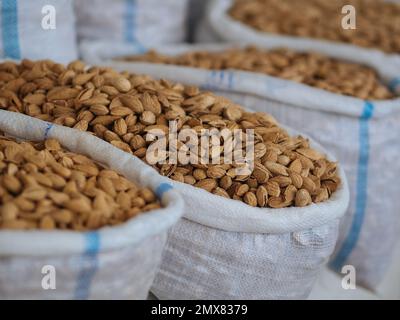 Mucchio di deliziosi pistacchi messi in sacchetti di plastica in stalla con vari tipi di noci in commercio Foto Stock