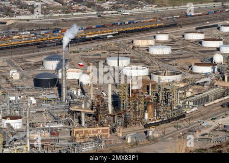 Una raffineria di petrolio e serbatoi di stoccaggio di petrolio vicino a Salt Lake City, Utah. Dietro ci sono i binari. Il vapore proviene da una torre di lavorazione. Foto Stock