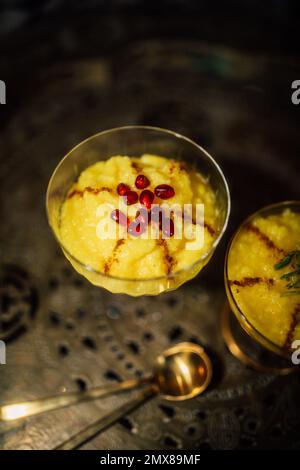 Sholeh Zard, un budino di riso allo zafferano persiano, dessert con melograno sul vassoio Foto Stock