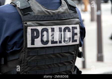 Primo piano marcatura 'POLIZIA' scritta sul retro di un giubbotto a prova di proiettile indossato da un ufficiale di polizia francese in una strada a Parigi, Francia Foto Stock