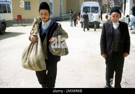 Contea di Sibiu, Romania, circa 1999. Gli uomini in una strada del villaggio nel loro abbigliamento domenicale e indossando i tradizionali cappelli di lana. Foto Stock