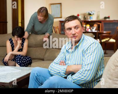 Marito sconvolto a parte sua moglie e madre anziana litigando Foto Stock