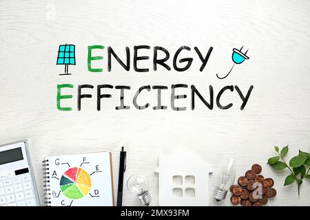 Concetto di efficienza energetica. Composizione piatta con grafico e figura della casa su sfondo di legno bianco Foto Stock