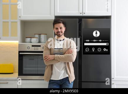 Un giovane uomo vicino a un frigorifero intelligente in cucina Foto Stock