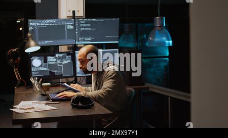 Sviluppatore di Web IT che confronta i file di dati su appunti cartacei e più monitor per programmare la nuova interfaccia server. Sviluppo di script html su una finestra terminale, codifica database. Scatto manuale. Foto Stock