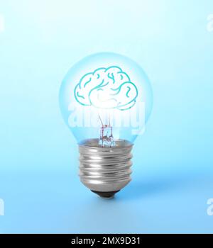 Lampadina con cervello umano all'interno su sfondo blu. Generazione di idee Foto Stock