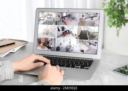 Donna che controlla le telecamere cctv moderne su laptop indoor, closeup. Sistema di sicurezza domestica Foto Stock