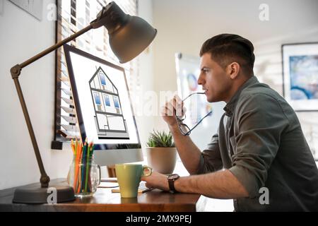 Ingegnere al lavoro. Uomo che proietta casa in ufficio Foto Stock