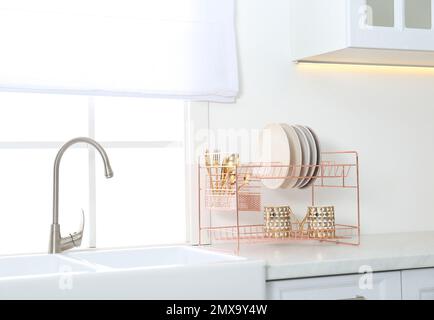 Griglia di asciugatura con piatti puliti sopra il lavandino in cucina
