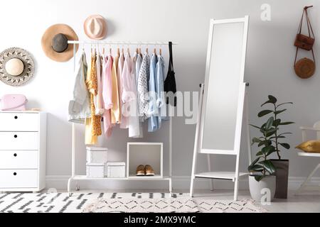 Rack con eleganti abiti da donna e specchio interno. Design degli interni Foto Stock