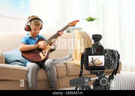 Piccolo insegnante di musica che registra lezioni di chitarra in interni Foto Stock