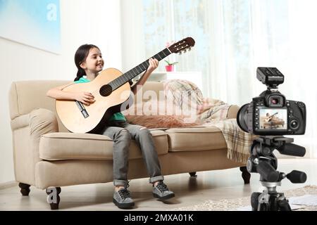 Piccolo insegnante di musica che registra lezioni di chitarra in interni Foto Stock