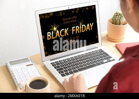 Black Friday. Donna che acquista online utilizzando un notebook a tavolo, in primo piano Foto Stock