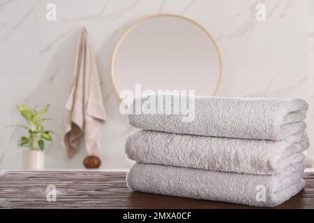 Una pila di asciugamani freschi su un tavolo di legno in bagno. Spazio per il testo Foto Stock
