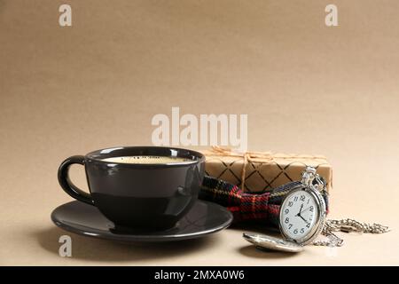 Composizione con caffè, cravatta e orologio su sfondo beige. Buon giorno del padre Foto Stock