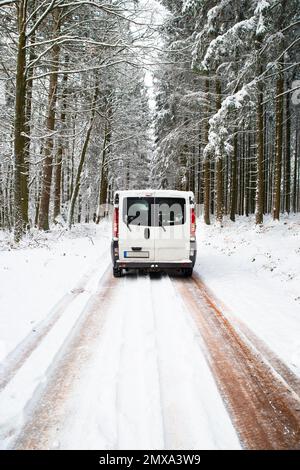 Camper Van guida su una strada attraverso una foresta coperta di neve in inverno, vacanza avventura e stile di vita nei boschi, Germania Foto Stock