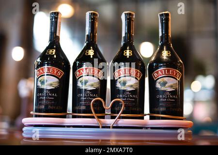 LVIV, UCRAINA - 26 OTTOBRE 2022: Baileys Irish Cream quattro bottiglie di vetro su uno stand di marca con illuminazione Foto Stock