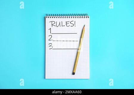 Blocco note con elenco di regole e matita su sfondo azzurro, vista dall'alto Foto Stock