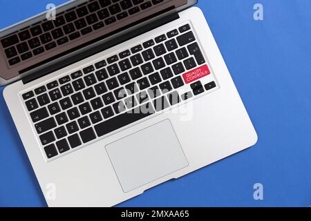 Moderno computer portatile con pulsante di controllo della qualità su sfondo blu, vista dall'alto Foto Stock