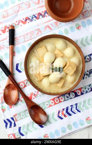 Vista dall'alto Opor Tahu Telur Puyuh o curry indonesiano con tofu e uovo di quaglia, servito sul Brown Bowl Foto Stock