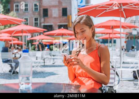 Donna che usa il telefono acqua potabile seduto un tavolo in New York City Street in Gansevoort Plaza, uno spazio pubblico nel Meatpacking District di NYC. Ragazza Foto Stock