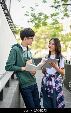 Giovani studenti asiatici felici di college che parlano e condividono idee su un progetto scolastico, avendo una bella conversazione dopo le lezioni. Foto Stock