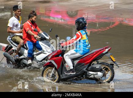 SAMUT PRAKAN, THAILANDIA, 25 2023 GENNAIO, la gente cavalca i motocicli attraverso le pozzanghere sulla strada Foto Stock