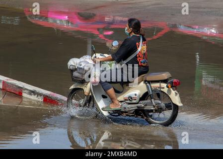 SAMUT PRAKAN, THAILANDIA, 25 2023 GENNAIO, Una donna con borse per lo shopping cavalca una moto attraverso la pozza Foto Stock