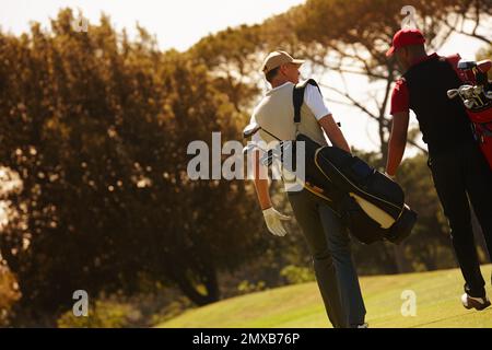 Quello era il gioco migliore di golf weve ha avuto. Immagine posteriore di due uomini che trasportano le loro borse da golf attraverso un campo da golf. Foto Stock