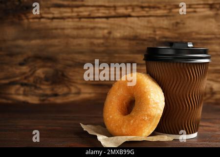 Deliziosa ciambella e una tazza di caffè sul tavolo di legno Foto Stock