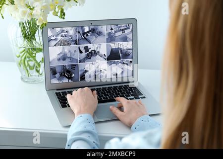 Donna che controlla le telecamere cctv moderne su laptop indoor, closeup. Sistema di sicurezza domestica Foto Stock
