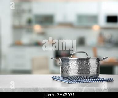 Asciugamano e pentola su tavolo in marmo in cucina. Spazio per il testo Foto Stock