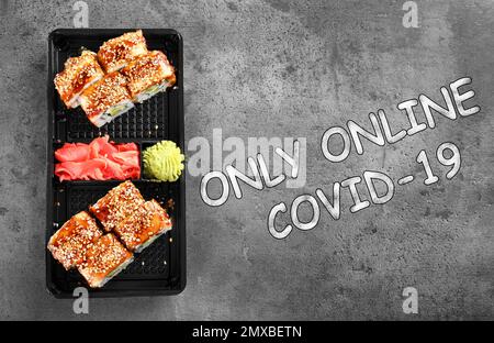 Gustosi panini sushi in scatola sul tavolo grigio, vista dall'alto. Servizio di consegna online di cibo Foto Stock