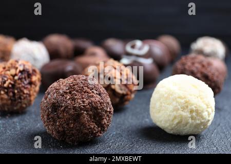 Diverse gustose caramelle al cioccolato su tavola nera, primo piano Foto Stock