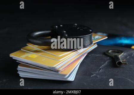 Carte di credito, lucchetto e chiave sul tavolo nero ardesia. Protezione dagli attacchi informatici Foto Stock