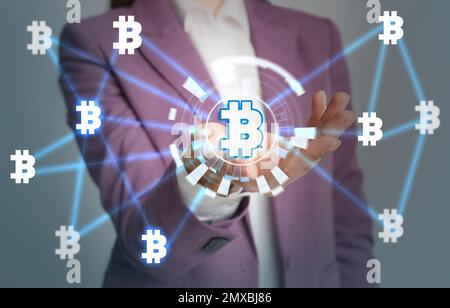 Concetto FinTech. Donna che mostra lo schema con simboli bitcoin Foto Stock