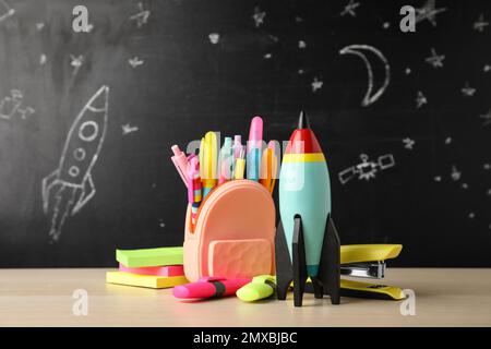 Razzo giocattolo luminoso e forniture scolastiche su tavolo di legno Foto Stock