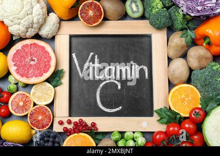 Prodotti diversi e lavagna con frase VITAMINA C sulla tavola Foto Stock