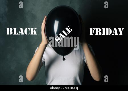 Concetto di Black Friday. Donna in possesso di palloncino con testo DI VENDITA su sfondo scuro Foto Stock