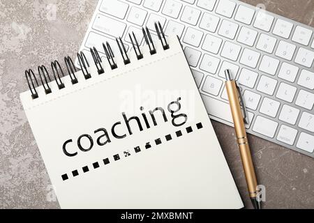 Apprendimento per adulti. Notebook con word coaching e tastiera su tavolo in marmo grigio, piano Foto Stock