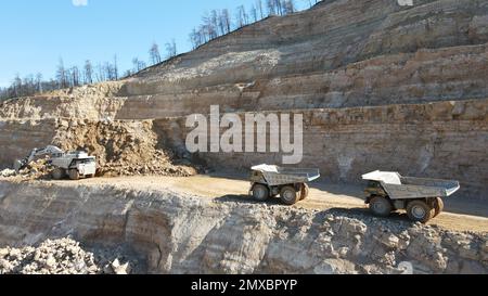 Dumper di carico per escavatori. Lavorano in un enorme cantiere. Foto Stock