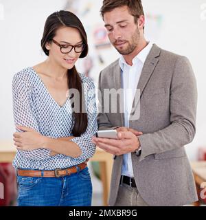 Un'idea coinvolgente. due colleghi in ufficio che guardano un tablet digitale. Foto Stock
