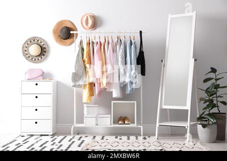 Rack con eleganti abiti da donna e specchio interno. Design degli interni Foto Stock