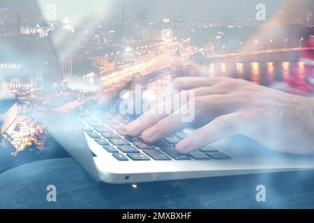 Doppia esposizione del programmatore maschio con laptop e cityscape, primo piano Foto Stock