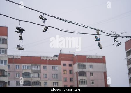 molte coppie di scarpe appendono in alto sui fili tra le case Foto Stock